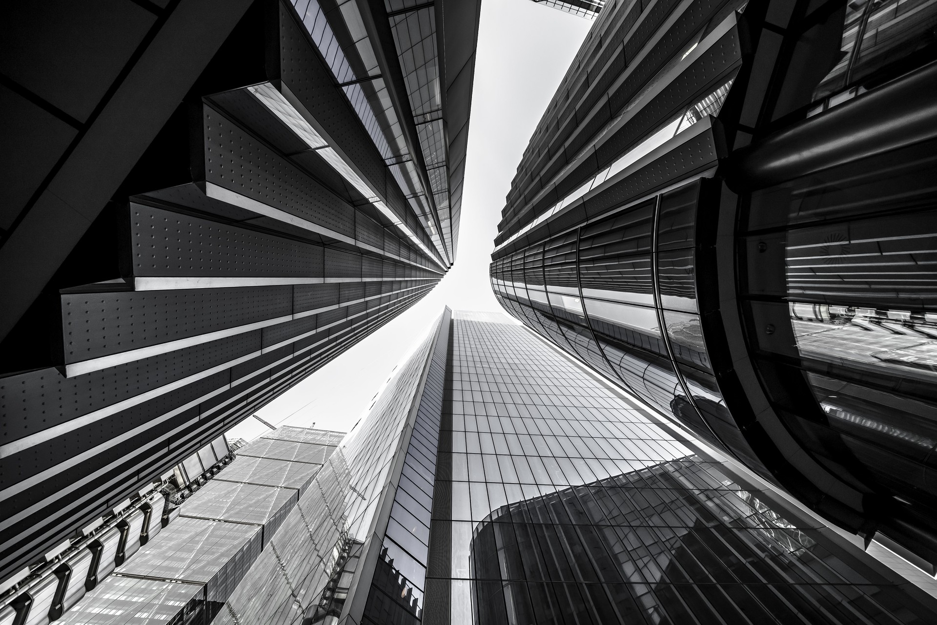 Low angle greyscale of modern skyscrapers with glass windows under sunlight